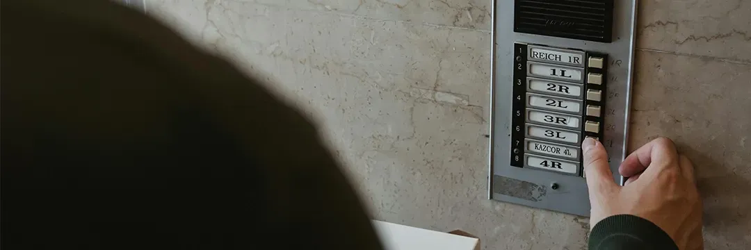 Person trycker på en dörrport med namn och lägenhetsnummer – illustrerar behovet av skyddad identitet och hur man får dold adress.