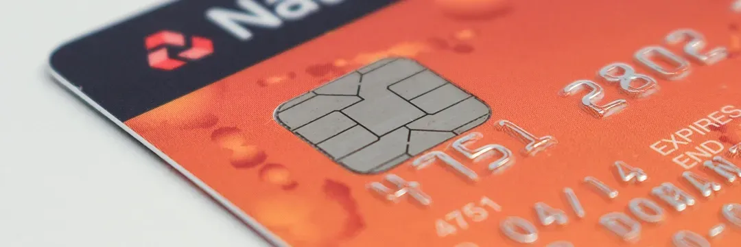 Närbild av ett orange bankkort med synligt chip – illustrerar risken för kortbedrägeri och obehöriga transaktioner.